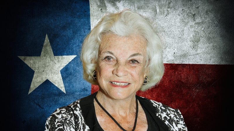 Sandra Day O'Connor Smiling in Front of The Texas State Flag