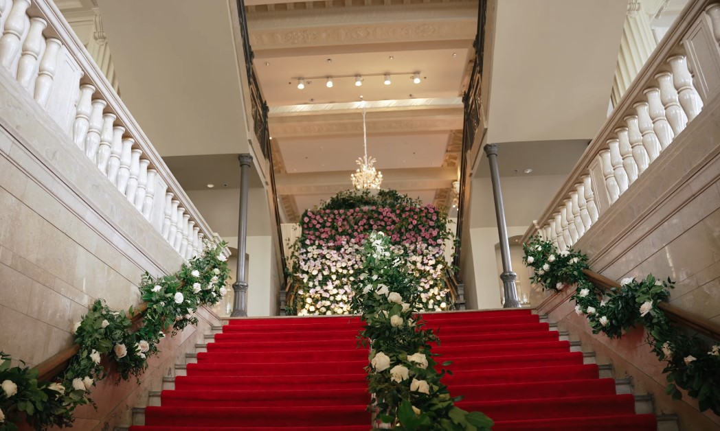 A red carpet staircase, beautifully decorated with floral arrangements