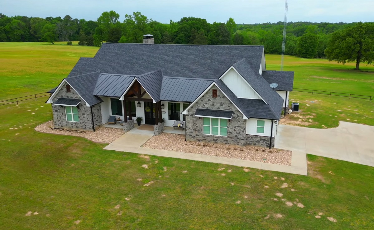 A picturesque aerial view of a ranch-style house surrounded by lush green fields