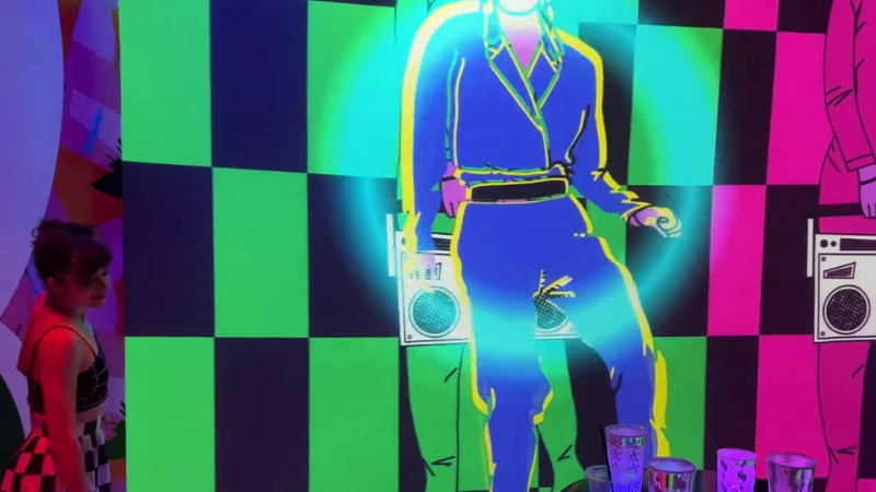 A guest watches a glowing dance projection during Meow Wolf’s ETNL Summer Series in Houston