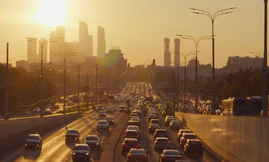 A city highway at sunset, heavy traffic stretching into the golden light