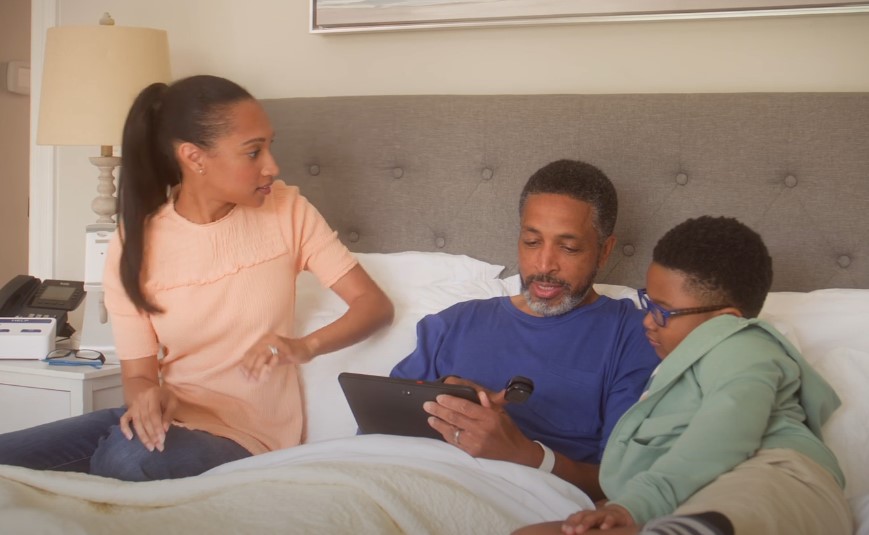 A man sit on a bed with two children