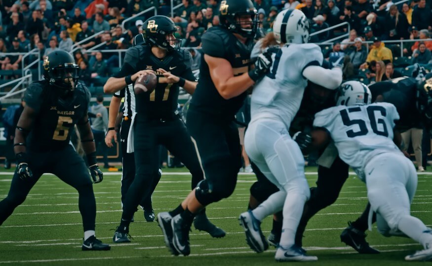 A quarterback prepares to throw the ball, while defenders close in
