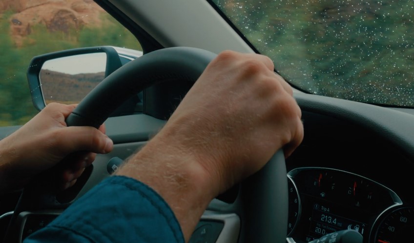 Man holding a steering wheel while driving a car