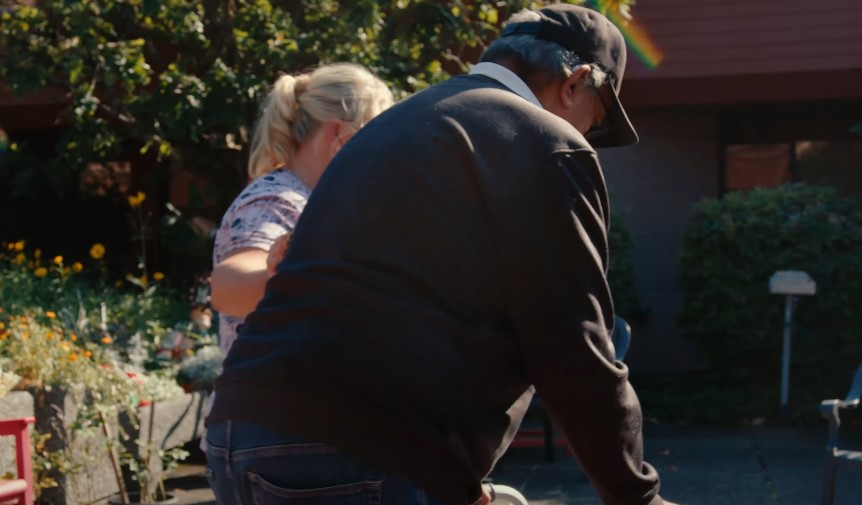 Sunlight highlights the backs of two people in a garden