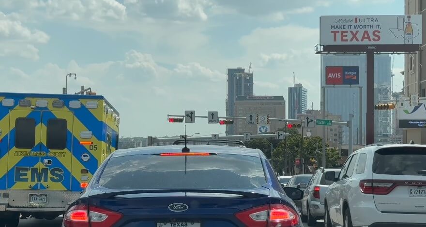 City traffic, a bustling scene, with an ambulance visible in the flow of vehicles