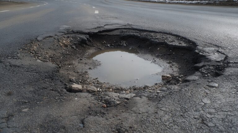 Large pothole filled with water on a Texas road, showing severe asphalt damage linked to the worst potholes in the state