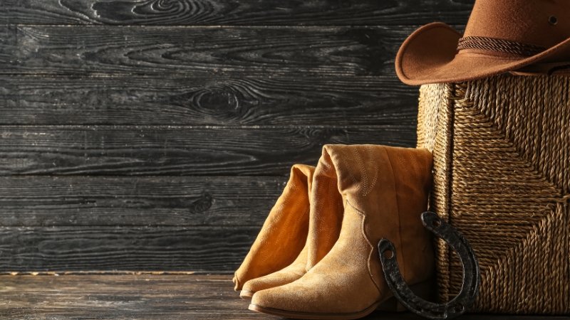 Cowboy boots, a hat, and a horseshoe beside a woven basket create a simple Texas pride starter kit