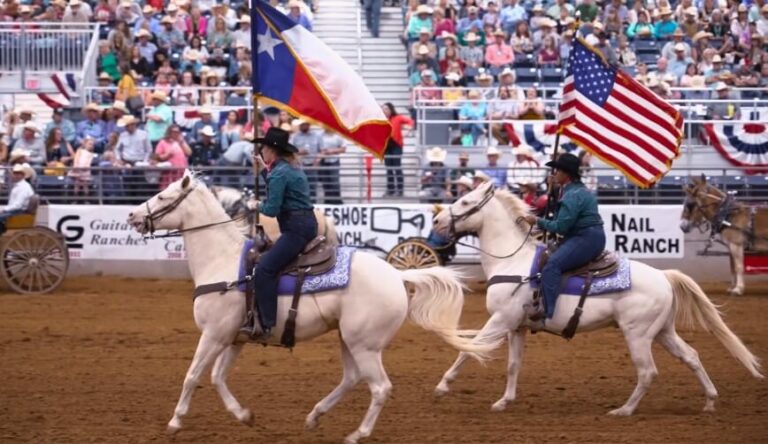 Riders on white horses carry the Texas and American flags before a cheering crowd