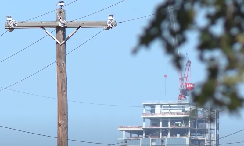 A power pole stands in the foreground with a tall building visible in the background