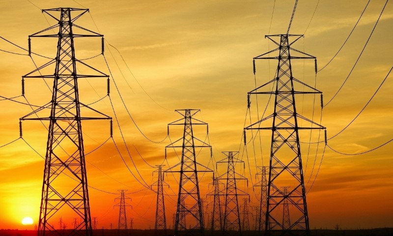 Electricity pylons silhouetted against a vibrant sunset sky over Texas
