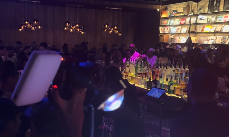 A bustling bar filled with patrons seated at tables, enjoying drinks and conversation in a lively atmosphere
