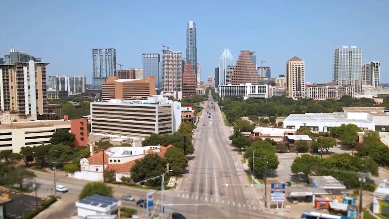Downtown Austin skyline with residential and commercial structures beside a wide street