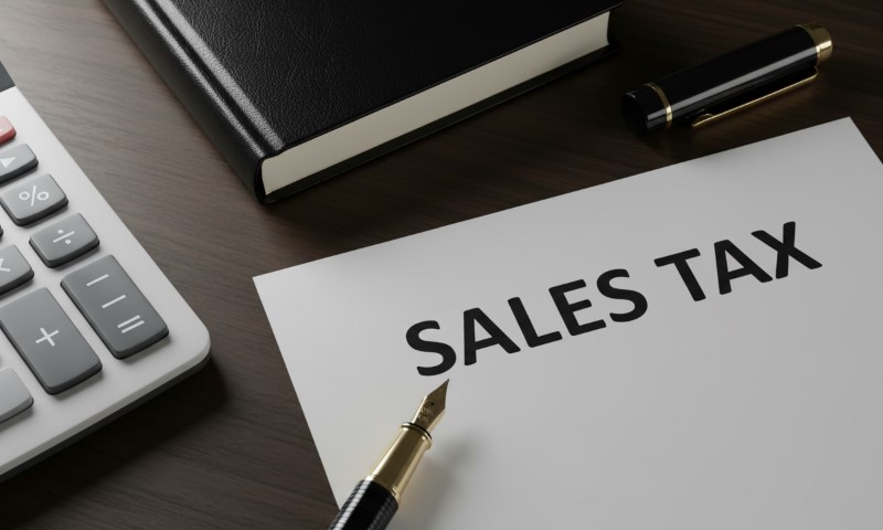 Sales tax document with a calculator and pen placed on a wooden desk