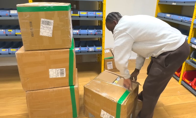 A man is stacking boxes on a shelf in a warehouse