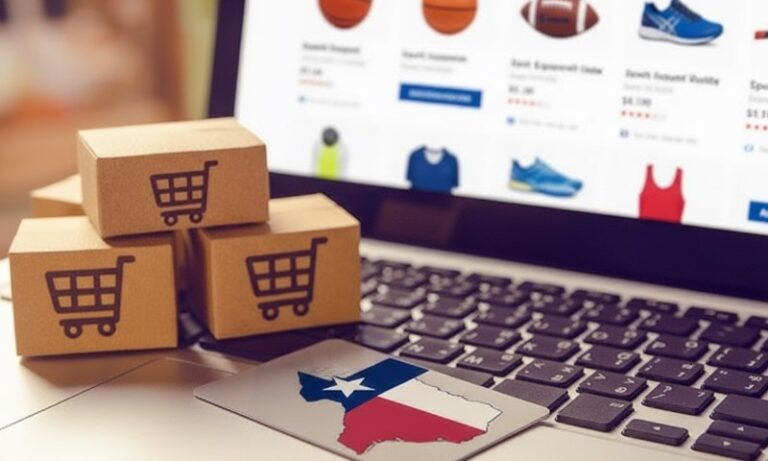 Three small cardboard shipping boxes with shopping cart icons sit next to a laptop displaying an online retail interface, with a Texas-shaped payment card resting on the keyboard
