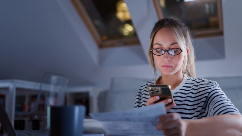 Woman reviewing utility bills on her phone inside an Austin apartment